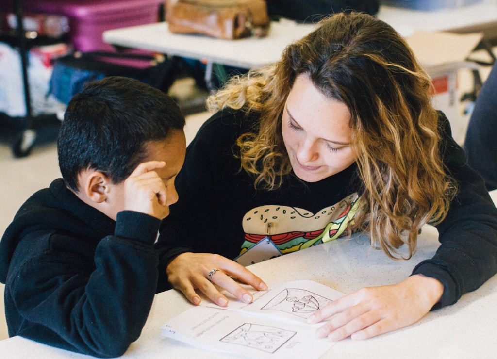 High school student Maria reads to young elementary student