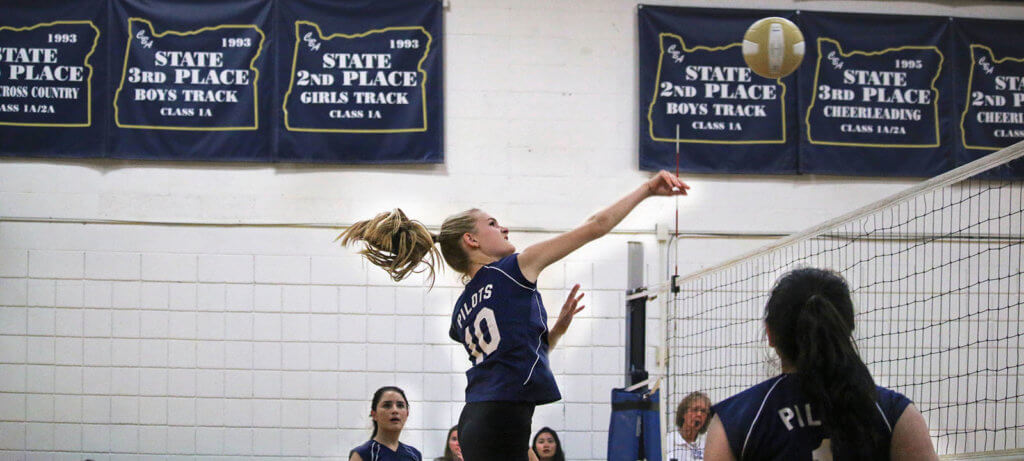 christian boarding school, girls' volleyball player, hits ball over the net, during high school game