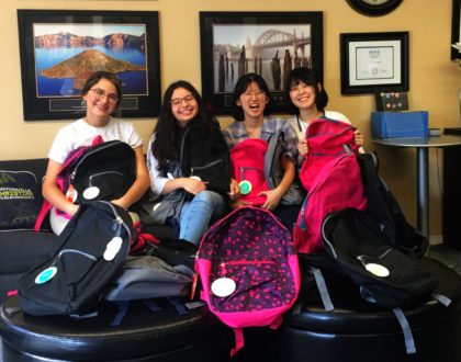 Four Canyonville Academy students pose with the backpacks filled with supplies to be donated to local schools